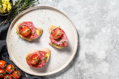 Salam soslu kanepeler, vişneli domatesler ve baget ekmekli mikro yeşiller. gri arka plan. Üst Manzara. Boşluğu kopyala.