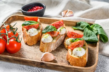 Domatesli sandviç, mozarella peyniri ve fesleğen. İtalyan aperatifi, antipasto. gri arka plan. en üstteki görünüm.