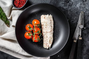 Çeri domatesli buğulanmış morina filetosu. Siyah arka plan. Üst görünüm.