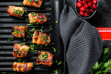 Domuz pastırmasına sarılmış kızarmış tavuk göğsü. Siyah arka plan. Üst görünüm