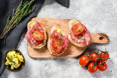 Salam soslu kanepeler, vişneli domatesler ve baget ekmekli mikro yeşiller. gri arka plan. en üstteki görünüm.