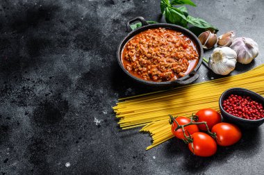 İtalyan spagetti bolonezi için yemek malzemeleri. Çiğ makarna, fesleğen, kıyma, domates. Siyah arka plan. Üst Manzara. Boşluğu kopyala.