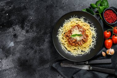 Domatesli spagetti bolonez makarna ve kıyma, parmesan peyniri ve fesleğen. Siyah arka plan. Üst Manzara. Boşluğu kopyala.