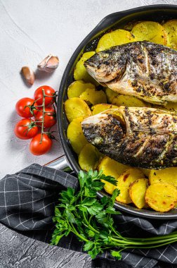 Tavada patates ile ızgara Dorado balığı. Gri arka plan. en üstteki görünüm.