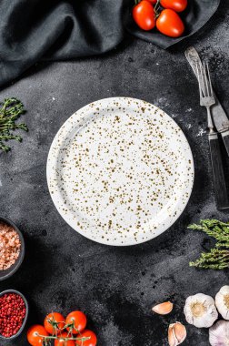 Taze çiğ sebze ve sebzelerin ortasında beyaz boş bir tabak. Sağlıklı, temiz yemek, vejetaryen, diyet yemek konsepti. Siyah arka plan. Üst Manzara. Boşluğu kopyala.