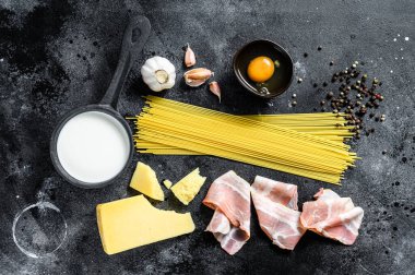 Geleneksel İtalyan Carbonara Makarnası. Pastırma, spagetti, parmesan peyniri ve pekorino peyniri, yumurta, sarımsak. Siyah arka plan. Üst görünüm.