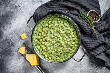 Pesto soslu patates gnocchi, parmesan peyniri ve ıspanak. İtalyan makarnası. gri arka plan. Üst görünüm.