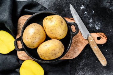 Kızarmış patates tarifi, tavada organik sarı patates. Siyah arka plan. Üst görünüm.