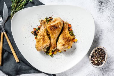 Beyaz tabakta sebzeli ızgara tavuk budu. Beyaz arka plan. Üst görünüm.