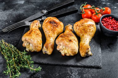 Baharatlı tavuk budu, baharatlı bacaklar ve otlar. Siyah arka plan. Üst görünüm.