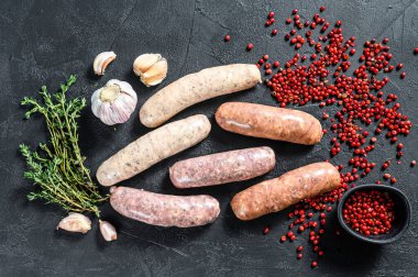 Kekik, sarımsak ve biberle çeşitli taze sosisler. Siyah arka plan. Üst görünüm.