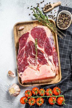 Çiğ haç kesilmiş et sapı, yemek pişirmek için gerekli malzemelerle dolu bacak. Gri arka plan. Üst görünüm.