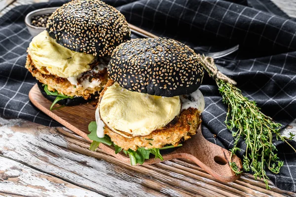 Burger with a black bun brioche, scrambled eggs, beef Patty and arugula. White background. Top view