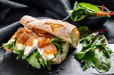 Keçi peynirli baget sandviç, armut reçeli, pazı ve ıspanak. Siyah arka plan. Üst görünüm.