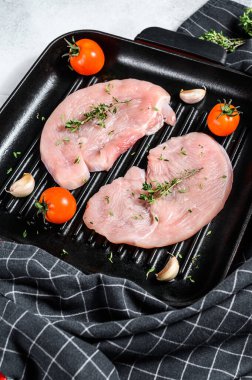 Tavada çiğ hindi bifteği. Taze göğüs eti. Beyaz arka plan. Üst görünüm.