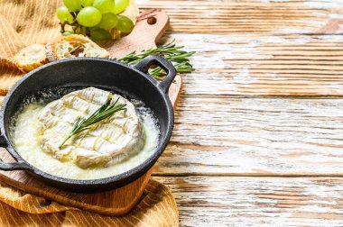Fırında peynir, tavada biberiyeli Camembert peyniri. Beyaz ahşap arka plan. Üst Manzara. Boşluğu kopyala.