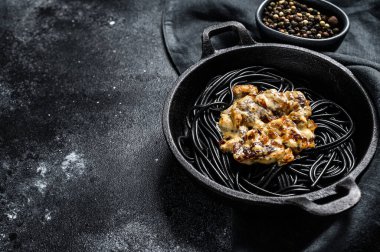 Tavada mürekkep balığı mürekkebi olan siyah spagetti makarna. Biber soslu biftek. Siyah arka plan. Üst Manzara. Boşluğu kopyala.