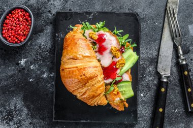 Peynirli, roka ve jambonlu kruvasan sandviç. Siyah arka plan. Üst görünüm.