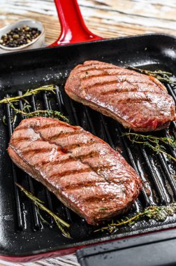 Kızartma tavasında ızgara et üst bıçaklı biftekler. Gri arka plan. Üst görünüm.