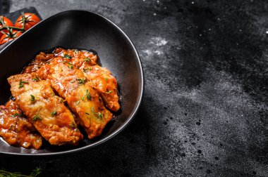 Fırında Tilapia balığı ve domates tabağı. Siyah arka plan. Üst Manzara. Boşluğu kopyala.