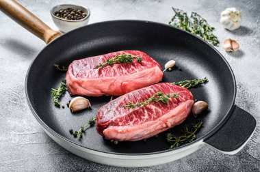 Çiğ mermer biftek, üst bıçak bifteği. Gri arka plan. Üst görünüm.