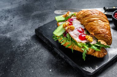 Peynirli, roka ve jambonlu kruvasan sandviç. Siyah arka plan. Üst Manzara. Boşluğu kopyala.