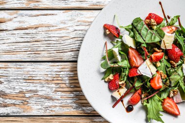 Camembert salatası, çilek, fındık, pazı ve roka. Beyaz arka plan. Üst Manzara. Boşluğu kopyala.