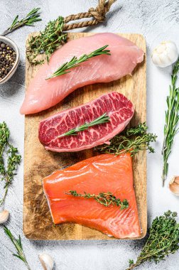 Üç çeşit biftek. Biftek bıçağı, somon filetosu ve hindi göğsü. Organik balık, kümes hayvanı ve sığır eti. Gri arka plan. Üst görünüm.