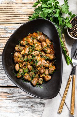 Tavuk ciğeri pişirilmiş kalpleri bir tabakta. Beyaz ahşap arka plan. Üst görünüm.