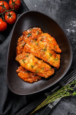 Fırında Tilapia balığı ve domates tabağı. Siyah arka plan. Üst görünüm.