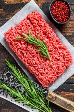 Çiğ et, kasap kağıdı üzerinde kıyma. Koyu ahşap arka plan. Üst görünüm.