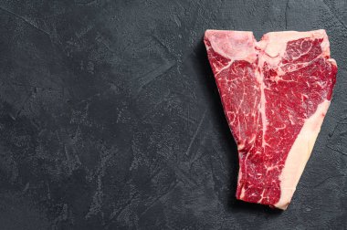 Kalın Raw T-Bone bifteği. Siyah arka plan. Üst Manzara. Boşluğu kopyala.