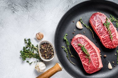 Tavada çiğ bıçaklı biftek. Gri arka plan. Üst Manzara. Boşluğu kopyala.