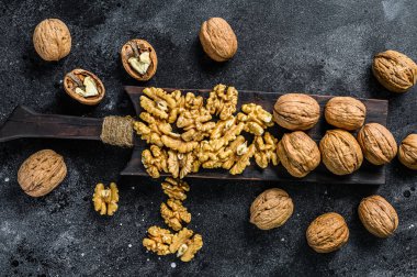 Tahta kesme tahtasındaki kabuklu ceviz çekirdekleri. Siyah arka plan. Üst görünüm.