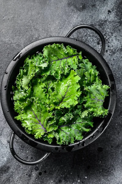 Green Kale salad in a colander. Organic Vegetarian food. Black background. Top view.