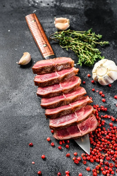 Sliced ready to eat steak Top Blade beef breeds, black Angus meat. Black background. Top view.