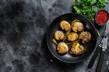 Köy fırınında pişmiş biberiyeli bebek patatesler. Siyah arka plan. Üst Manzara. Boşluğu kopyala.