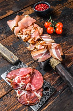 Soğuk, kurutulmuş İtalyan eti jambonu, jambon, pancetta, pastırma. Koyu ahşap arka plan. Üst görünüm.