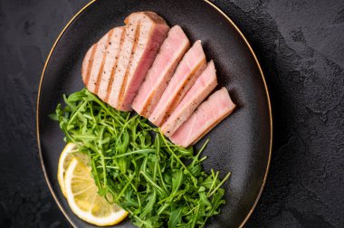 Lezzetli ızgara ton balığı bifteği, canlı renkler ve zengin bir tat, yaz barbeküleri ve zarif yemekler için mükemmel. Siyah arka plan. en üstteki görünüm.