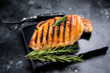 Grilled chicken breasts steaks with rosemary, farm poultry meat, top view, black background