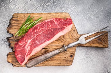 Uncooked striploin steak or strip New York on a wooden cutting board, inviting you to create mouthwatering recipes for any occasion. white background. top view.
