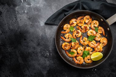 Tavada sarımsaklı ve tereyağlı karides kızartması. Siyah arka plan. Üst görünüm.