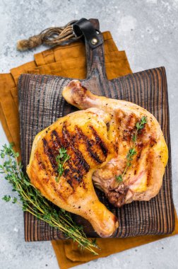 Roast chicken legs with Thigh on wooden cutting board, grilled poultry meat on gray background, top view.