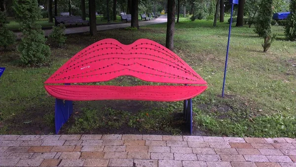 Bench for lips-shaped kisses in a city park. Red lips.