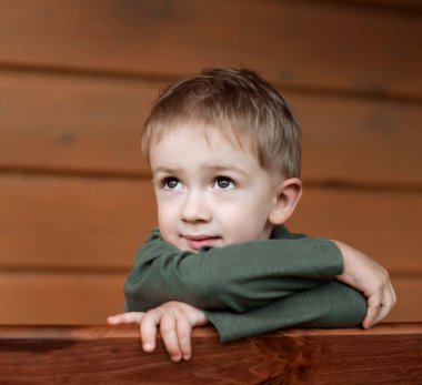 Çocuk tahta bir bankta oturuyor.