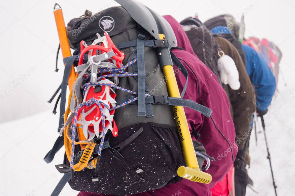 Climbing equipment; snow shovel on a backpack; climbing cats; ice ax; Team of climbers on the trail; Climbers in the snow;