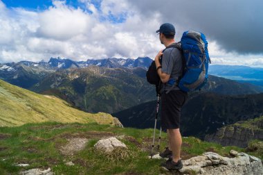 Bir sırt çantası ile Turist; büyük sırt çantası; elinde trekking çubukları; turist dağlara bakar; bir adam mesafeiçine bakar;