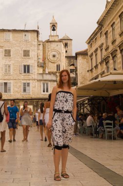 Split, Dalmaçya, Hırvatistan; 09/07/2018: Kızıl saçlı kız bir ortaçağ şehrinde yürüyor. Split şehrinin alanı. Saat kulesi.