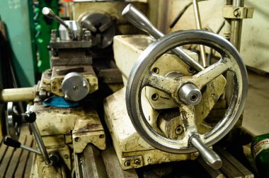 Metal atölyesi, metal işleme makineleri. Makinenin kontrol kolları. Atölyeye kurulmuş ekipman, kapatma yönetim araçları.