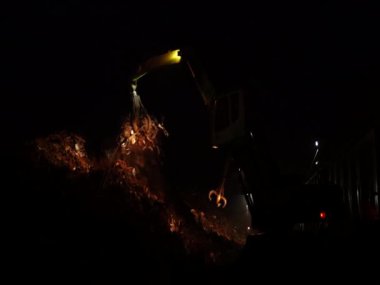 Geceleri büyük bir manipülatörden hurda metal yükleniyor.